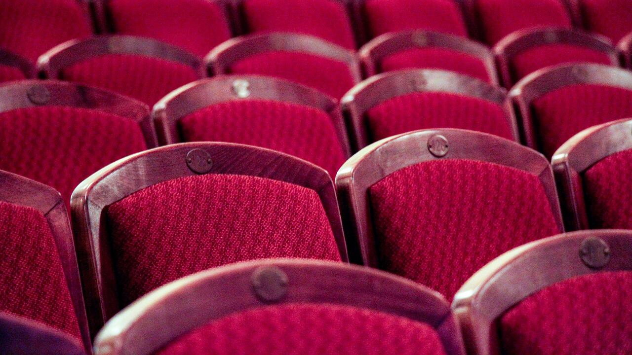 Das Bild zeigt leere Stühle in einem Theater.